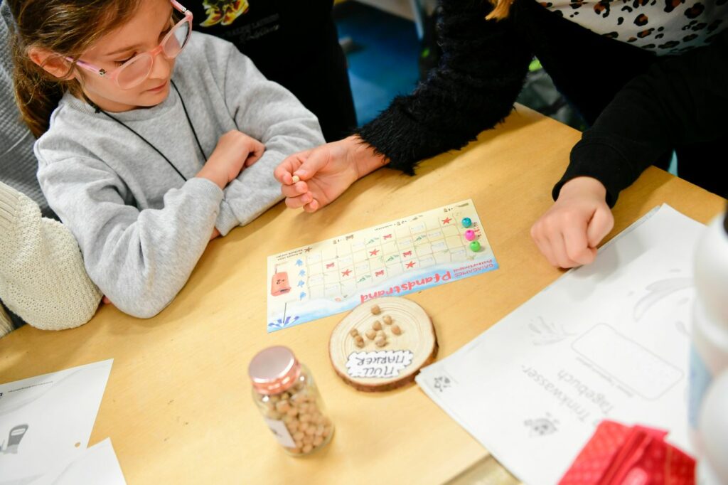 Kinder einer Wasserschule spielen ein Müllspiel